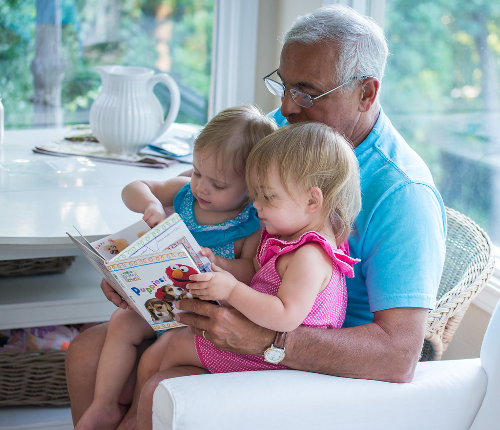 A grandparent reading a picture book with two small grandchildren at home